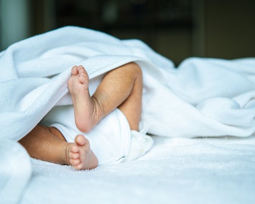 Newborn baby feet on a white blanket.